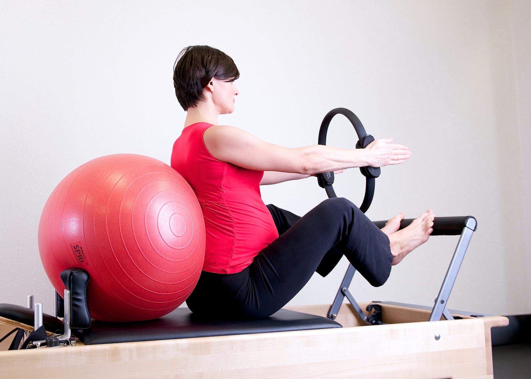 woman in red top leaning on red stability ball