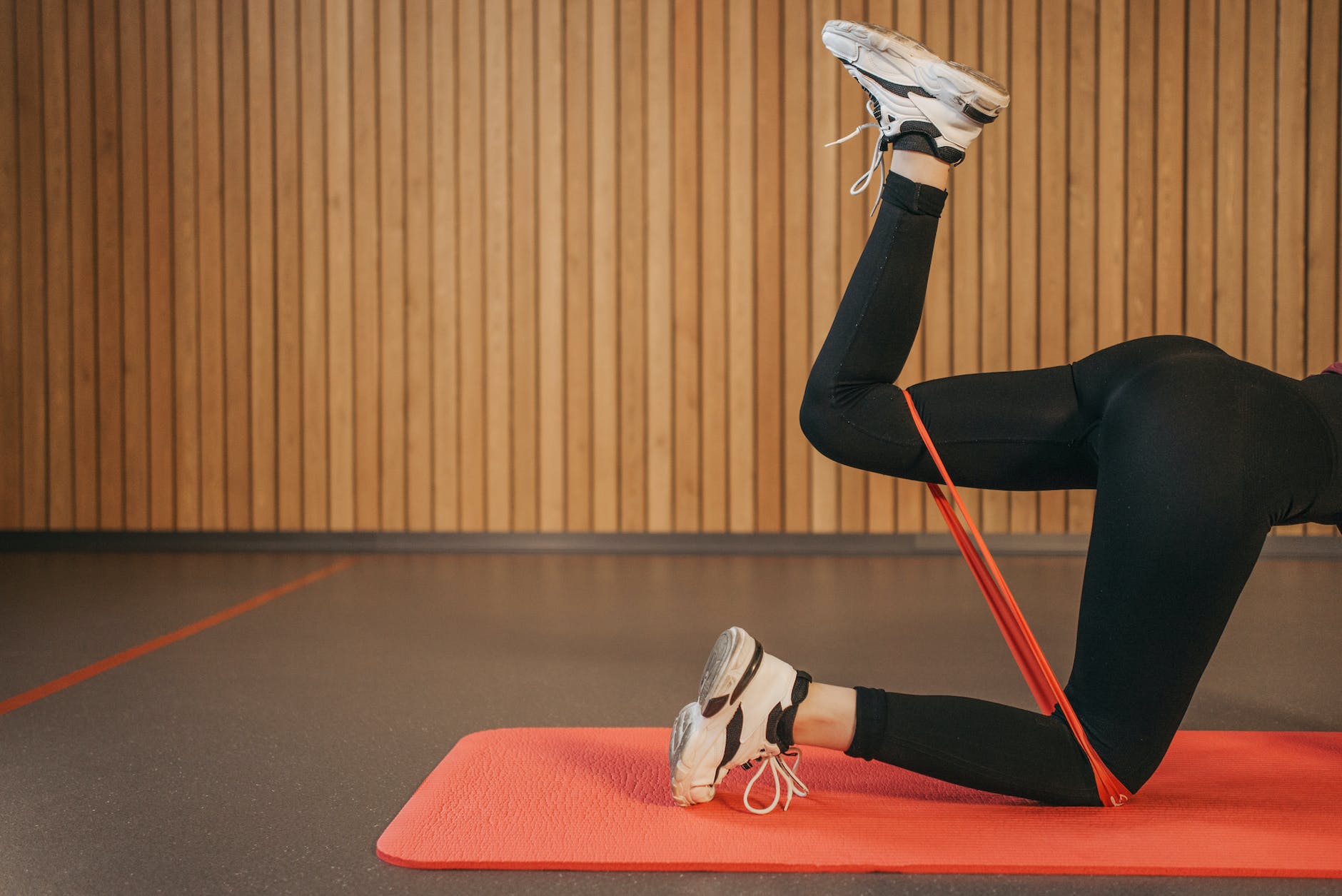 person in black leggings doing leg exercise with a resistance band