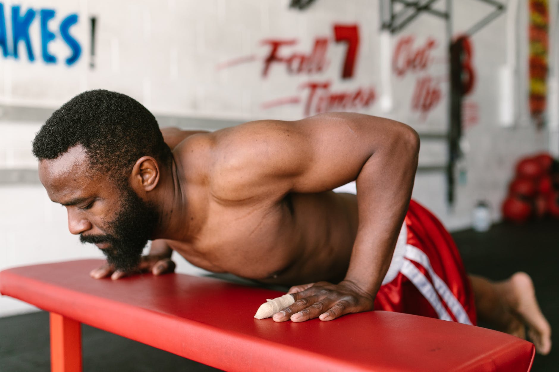 close up shot of a man doing push ups on a red bench